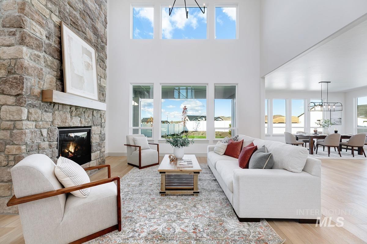 Living area with a chandelier, light wood-style flooring, a fireplace, and a high ceiling