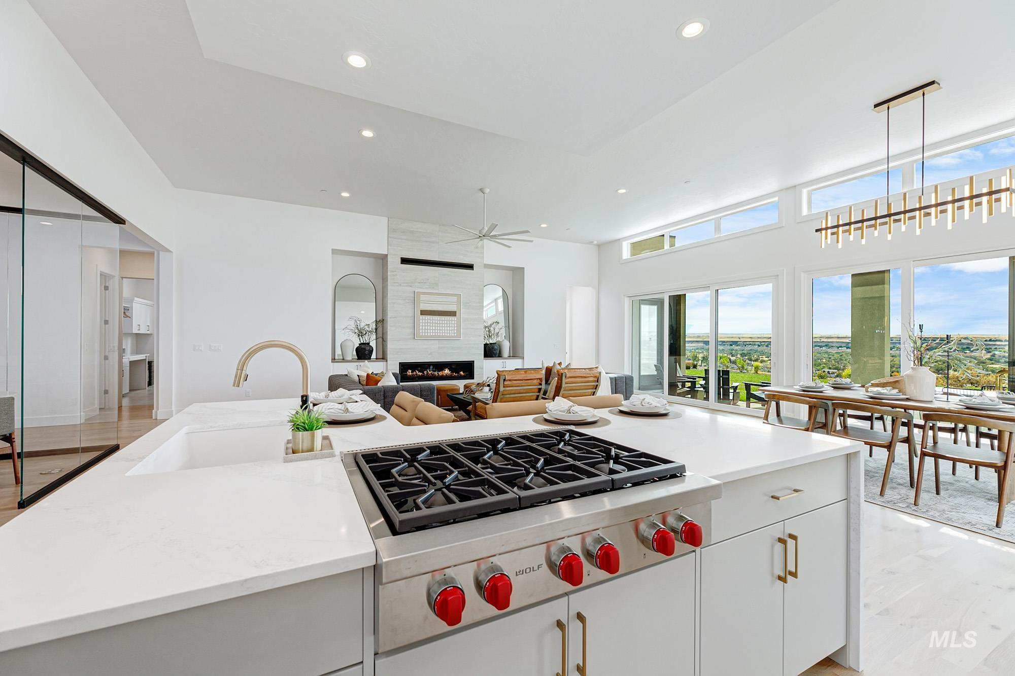 Kitchen with white cabinetry, light wood-type flooring, stainless steel gas cooktop, a fireplace, and light stone counters