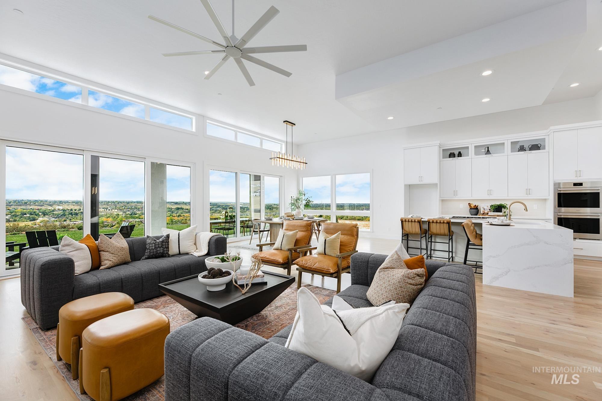 Living area with light wood-type flooring, a ceiling fan, recessed lighting, and a high ceiling