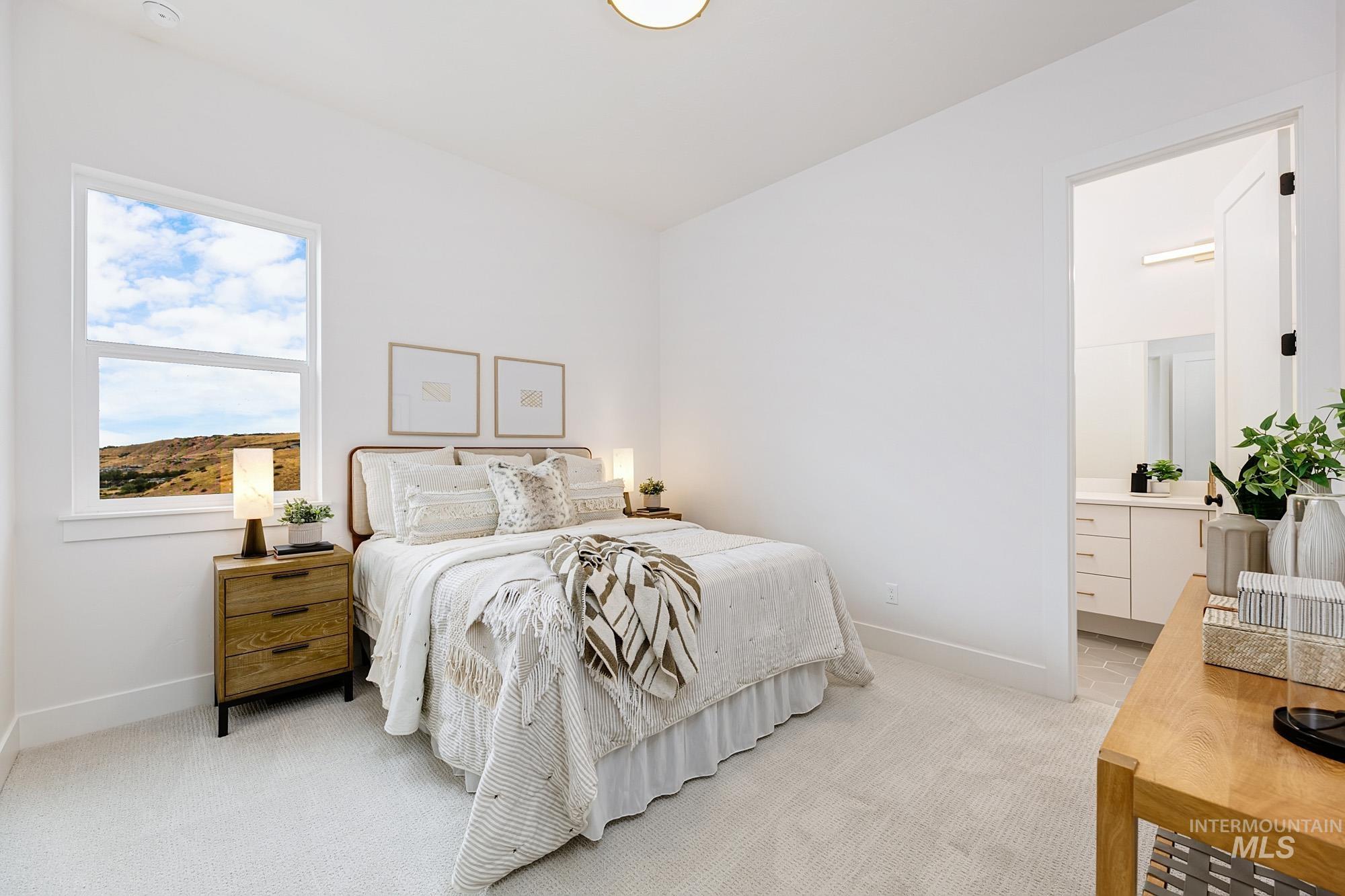 Bedroom featuring light carpet and ensuite bathroom