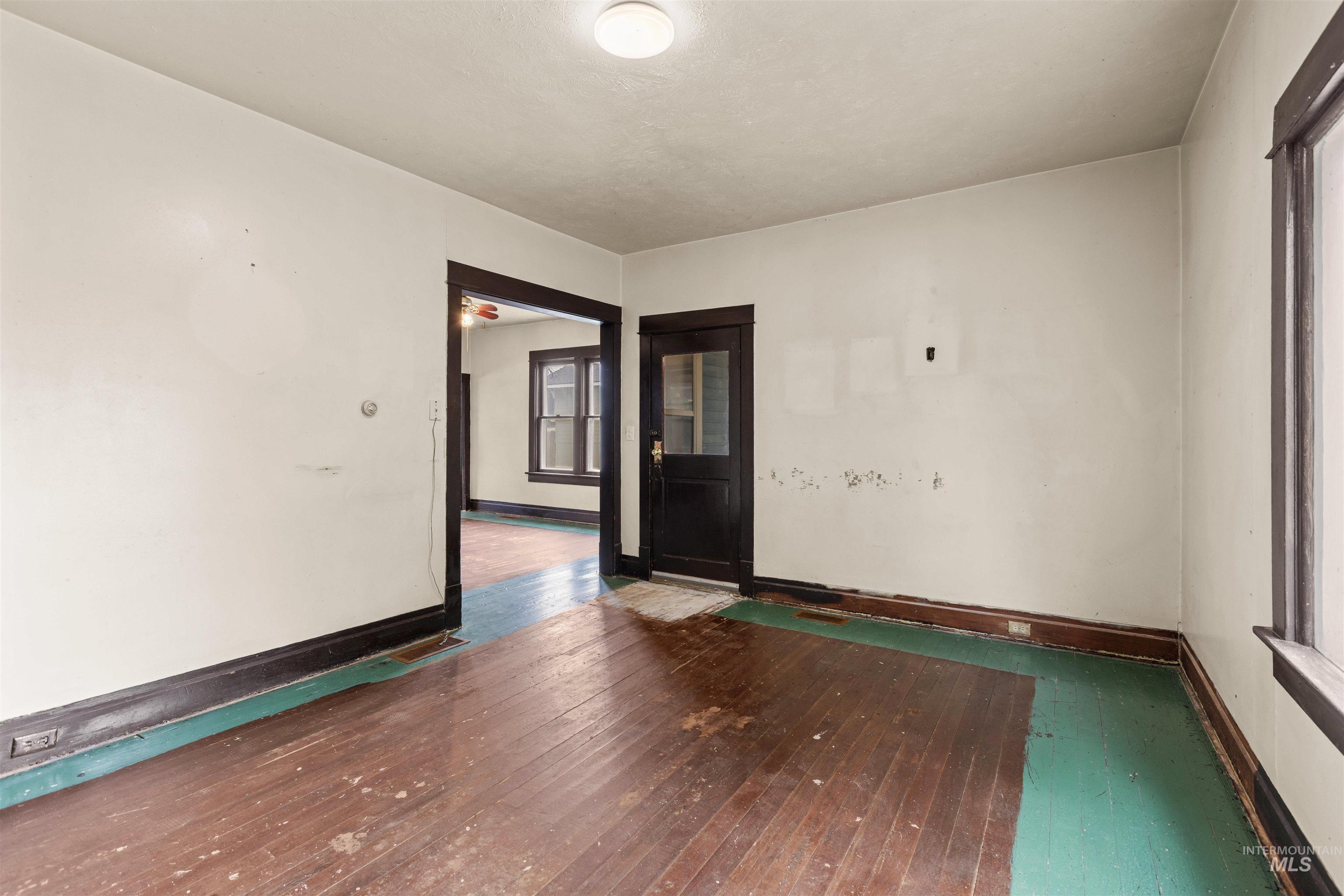 Room with wood-finish flooring, white walls, and dark trim