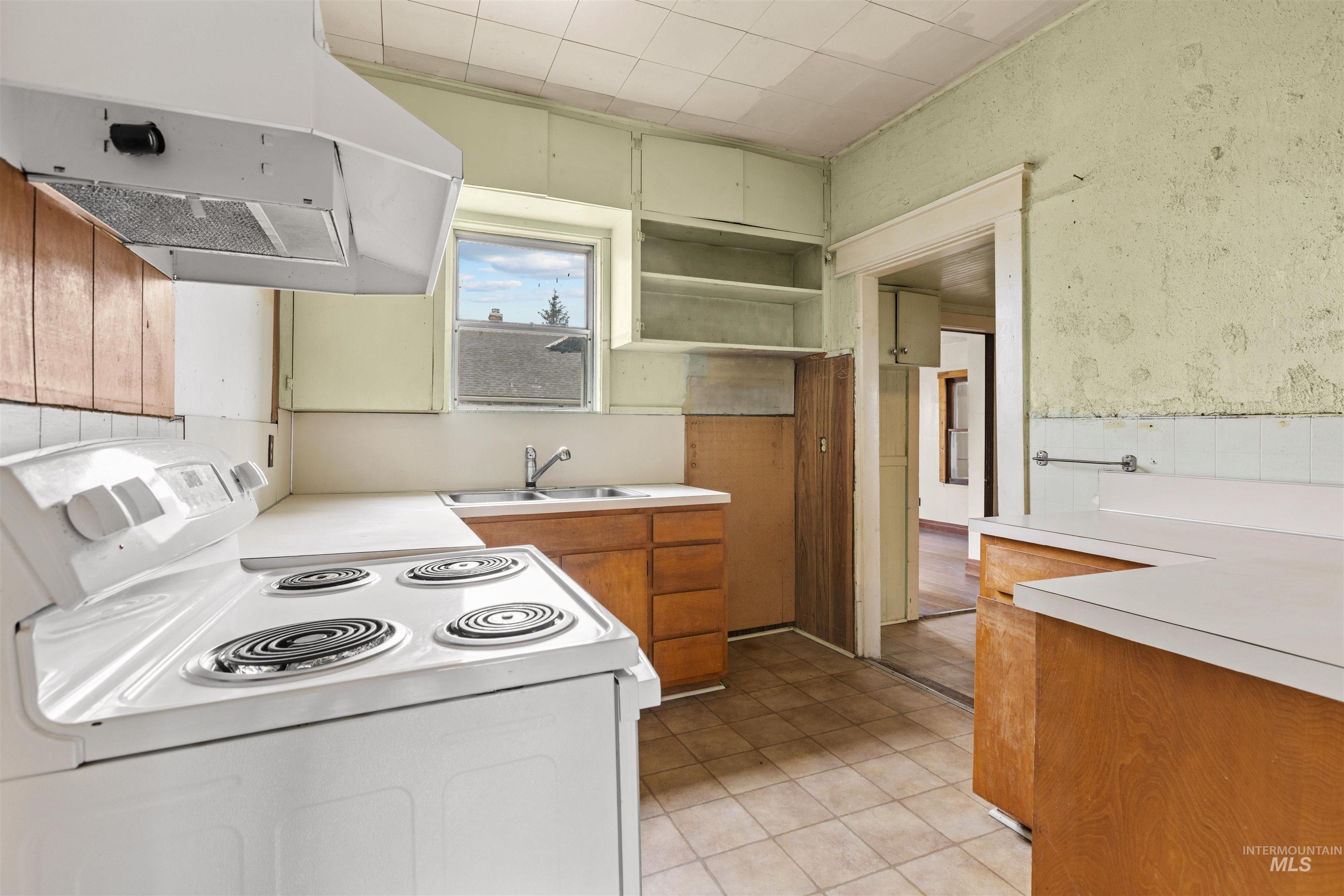 Kitchen featuring a white electric range with a range hood, wood-finish cabinetry, white countertops, and a double-basin sink