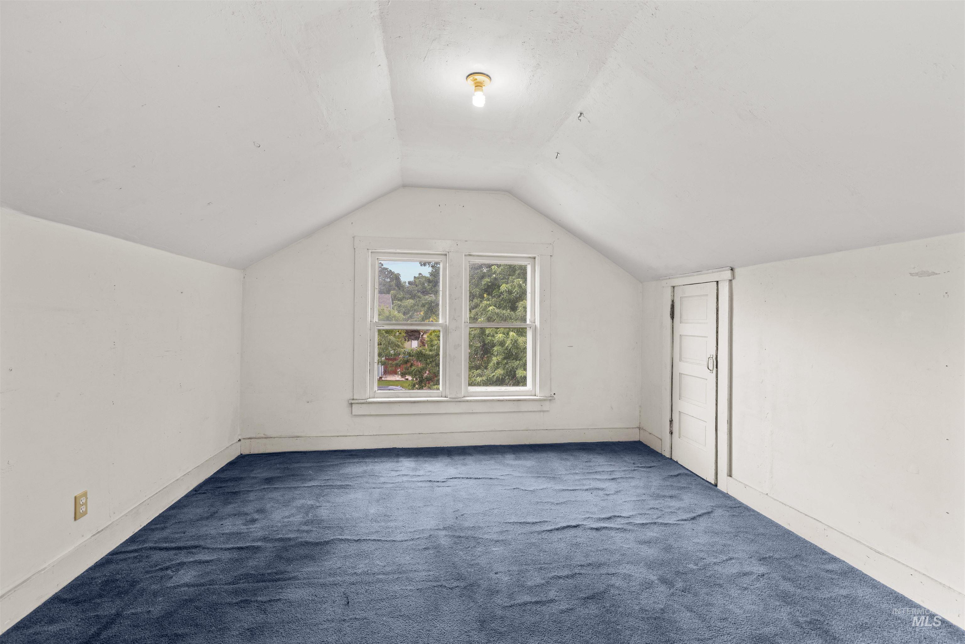 Attic space featuring blue carpeting, a white painted ceiling, and white painted walls