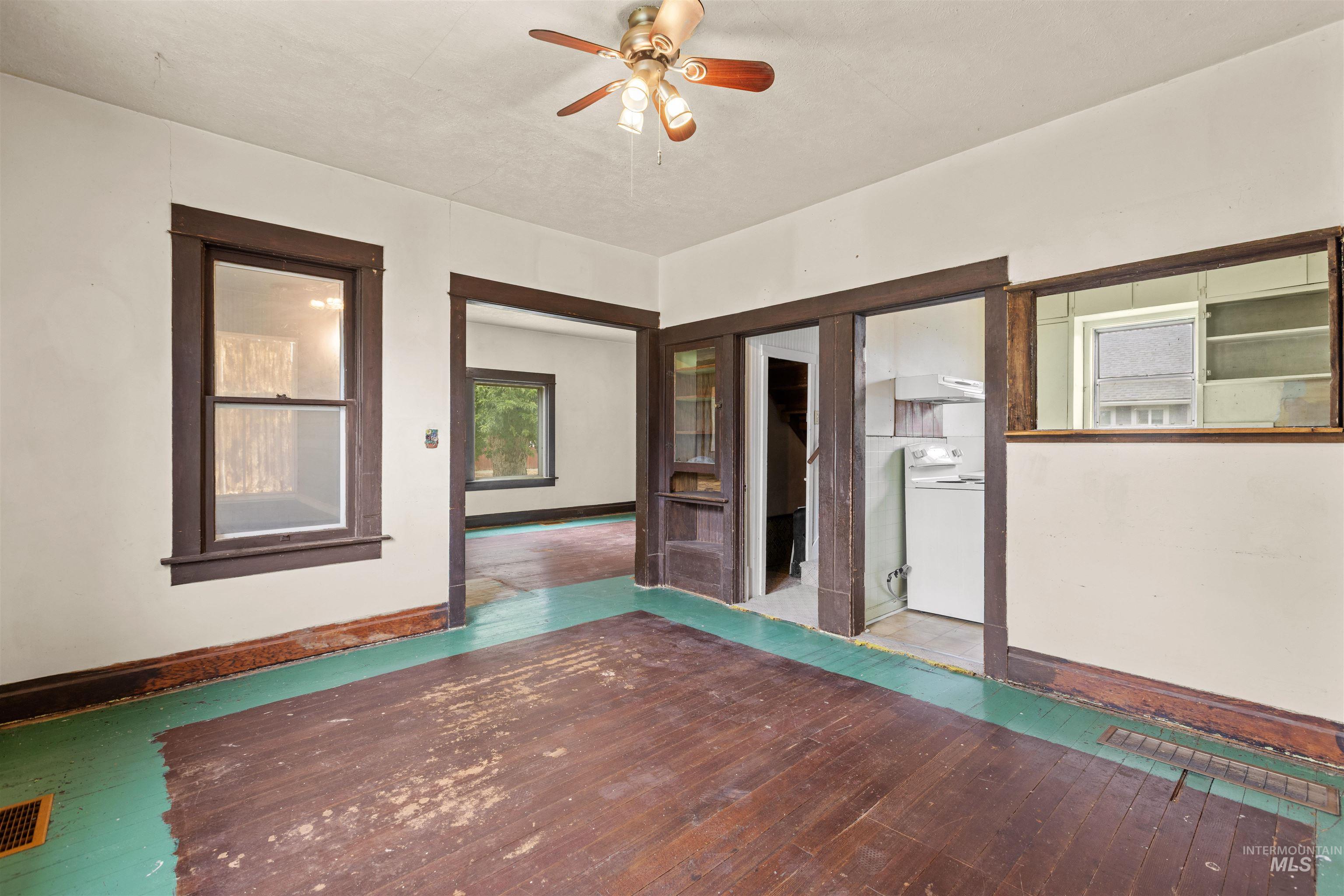 Interior space featuring exposed wood-finish flooring, white painted walls, and dark wood trim