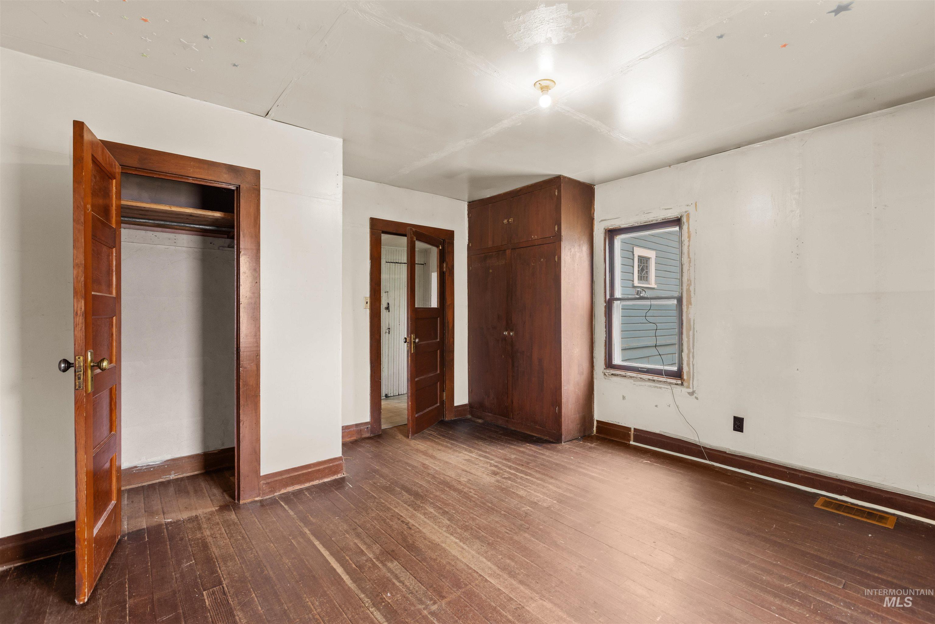 Hardwood flooring, wood-paneled doors, a built-in wood cabinet, and a window with wood trim