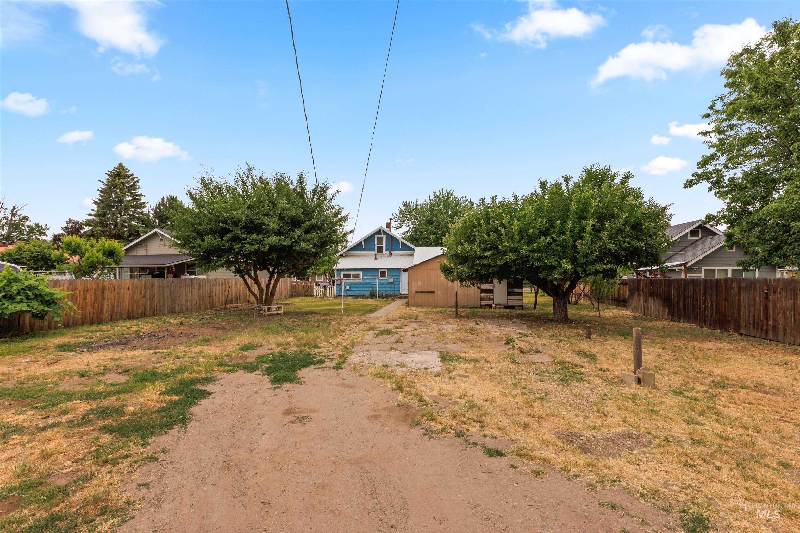Expansive backyard featuring mature trees, a wood privacy fence, and a dedicated concrete pad