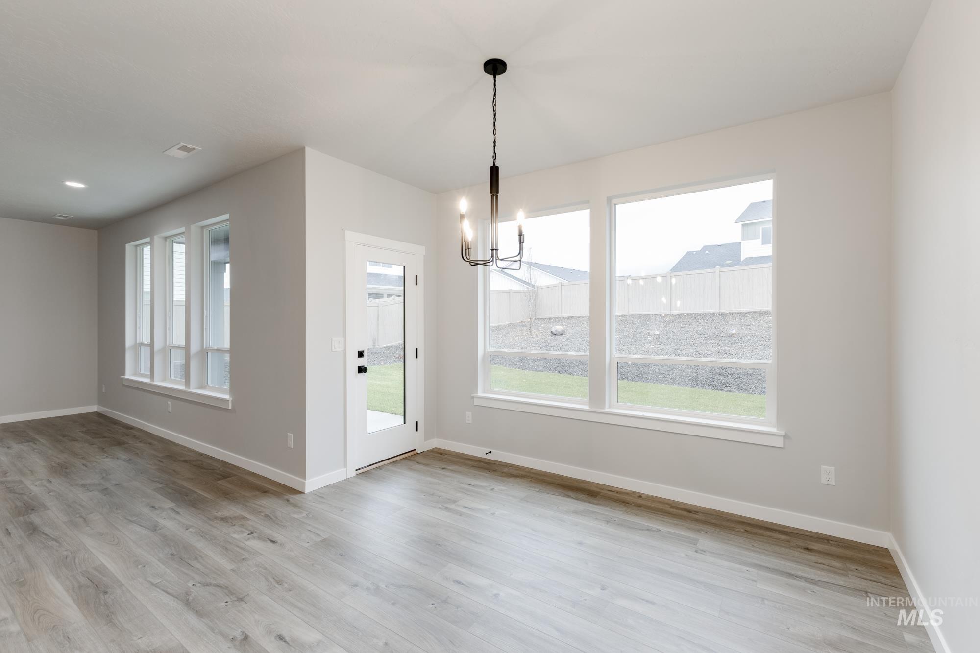 Unfurnished dining area featuring a chandelier, light wood-type flooring, and plenty of natural light