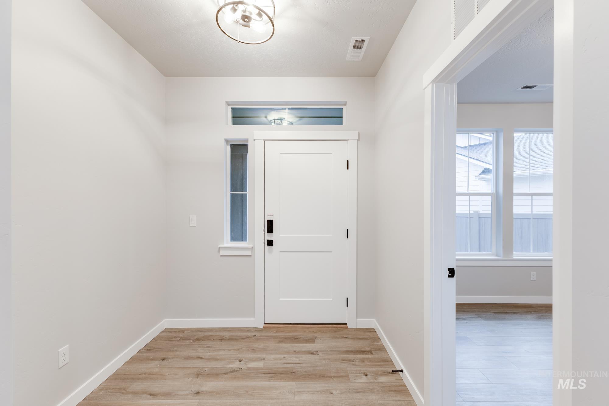 Foyer entrance with light wood-style floors and baseboards