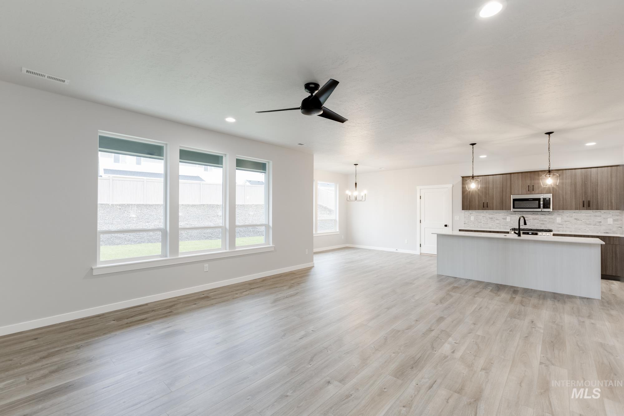 Unfurnished living room with ceiling fan, a chandelier, recessed lighting, and light wood-style floors