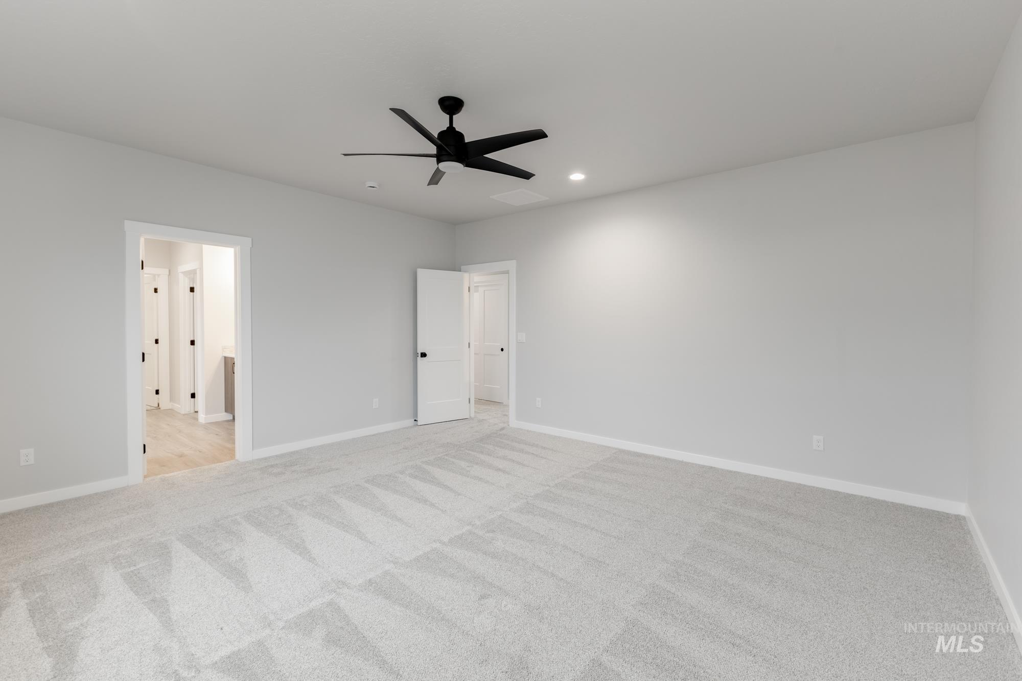 Unfurnished bedroom with a ceiling fan, light colored carpet, recessed lighting, and ensuite bath