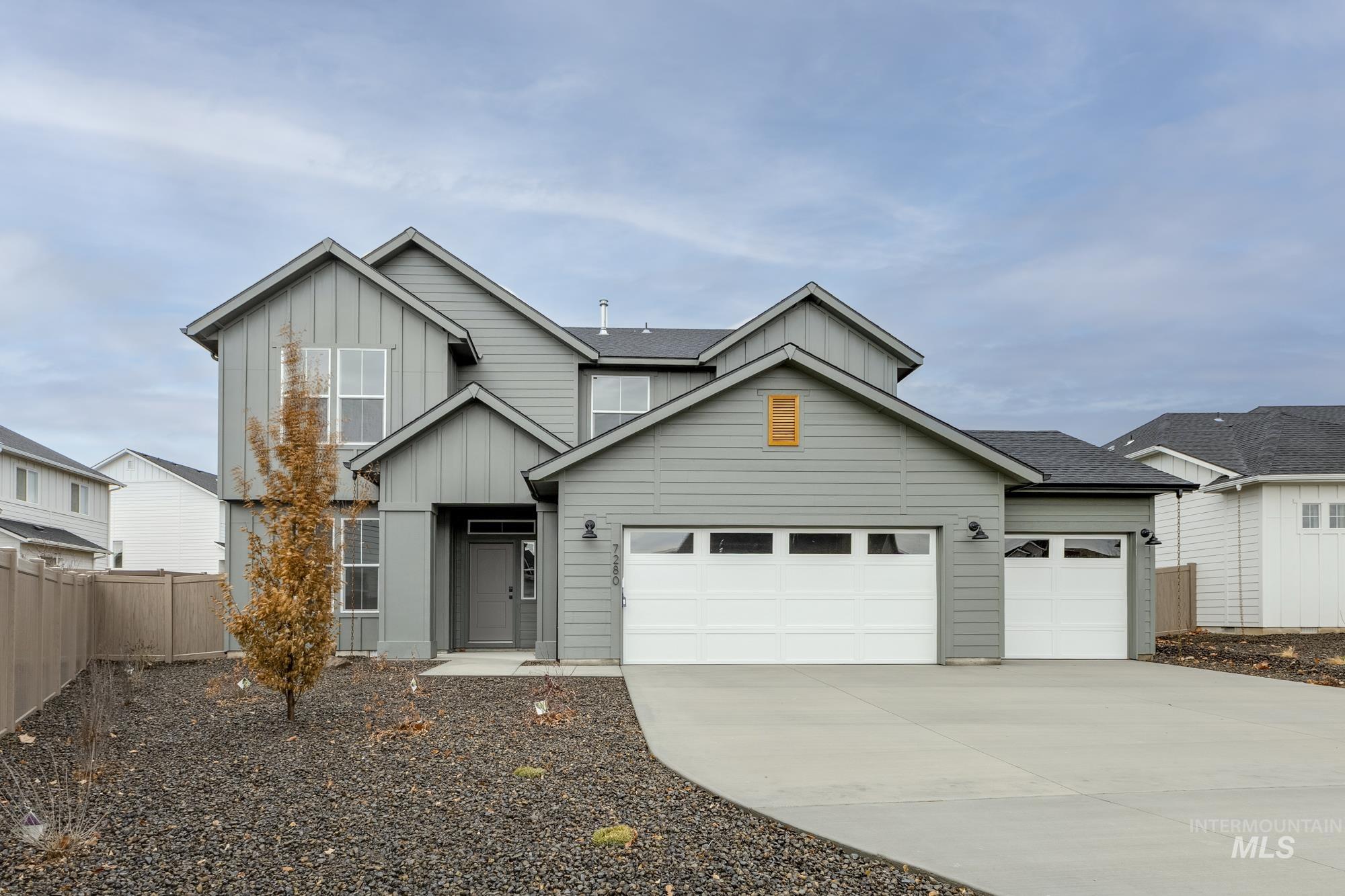 View of front of property with board and batten siding, driveway, an attached garage, and roof with shingles