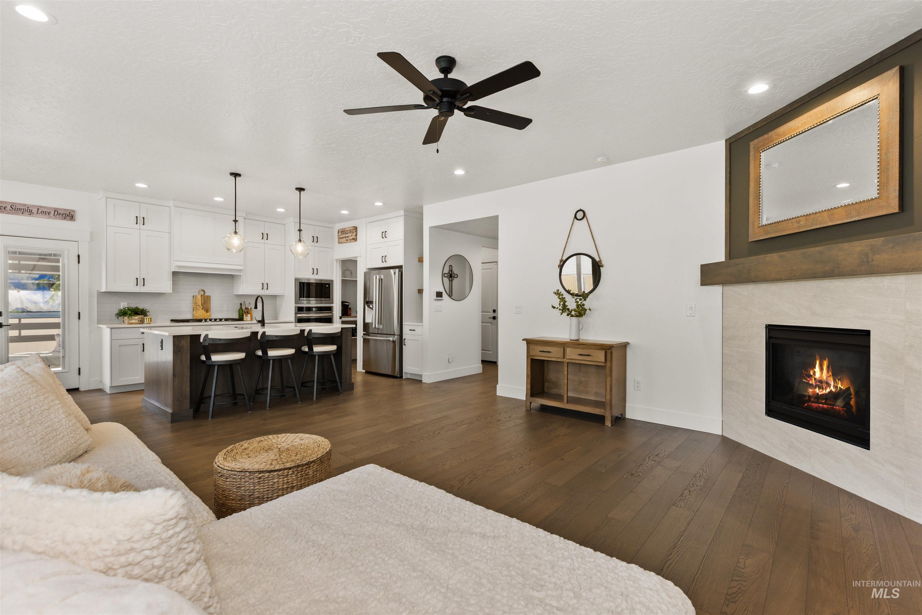 Living area with dark wood-style flooring, recessed lighting, ceiling fan, and a tile fireplace