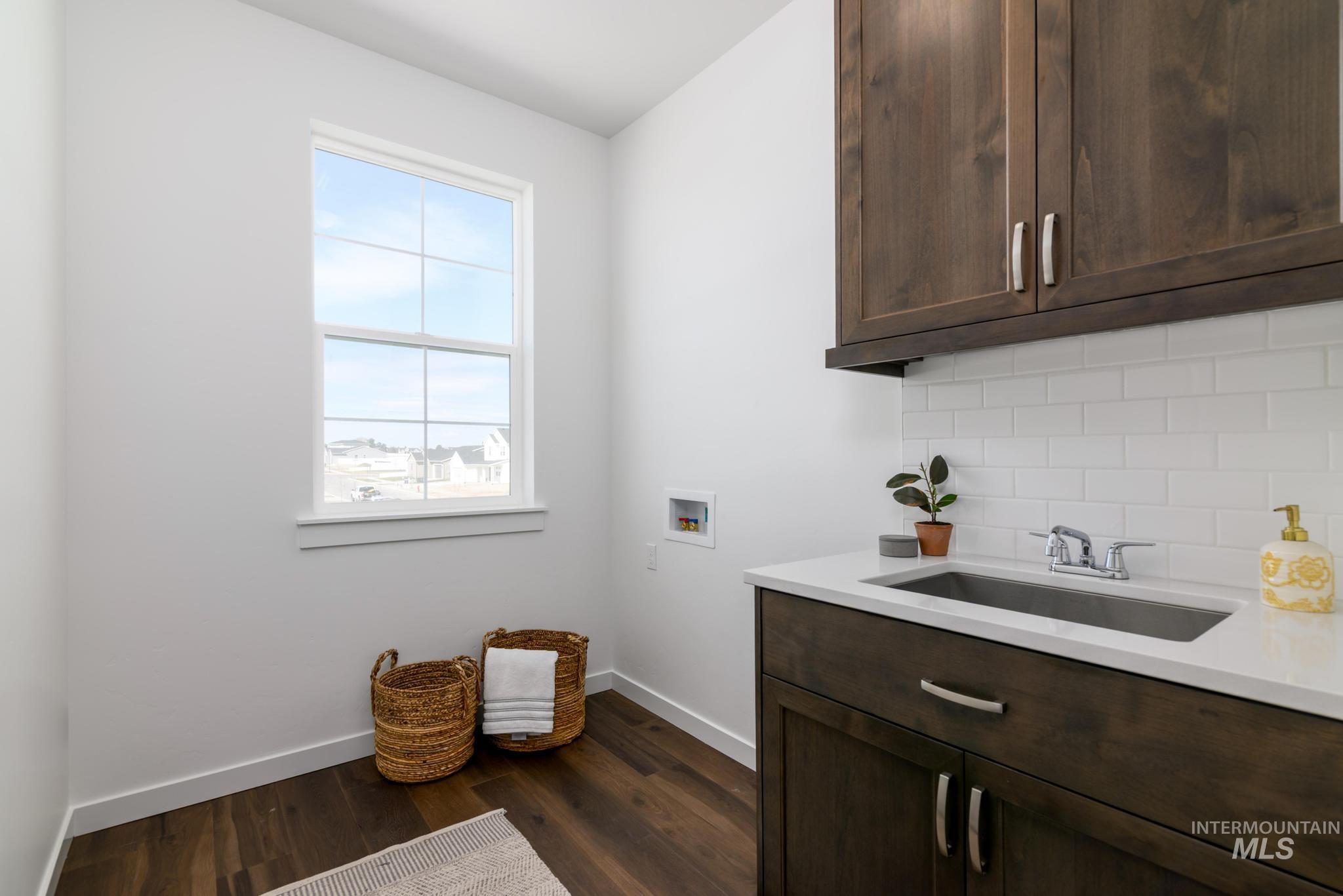 Laundry room with cabinet space, hookup for a washing machine, and dark wood finished floors
