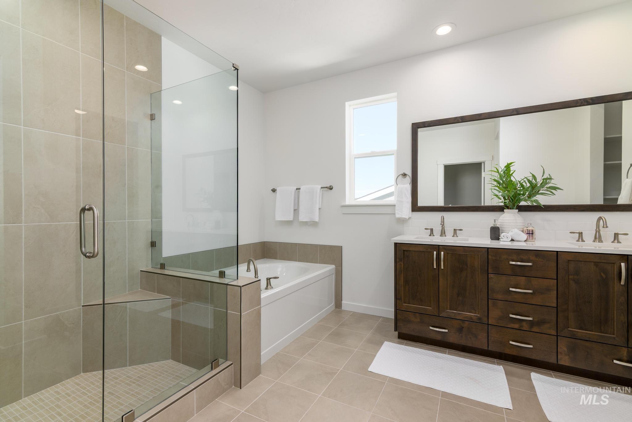 Bathroom featuring light tile patterned flooring, a stall shower, a garden tub, double vanity, and recessed lighting