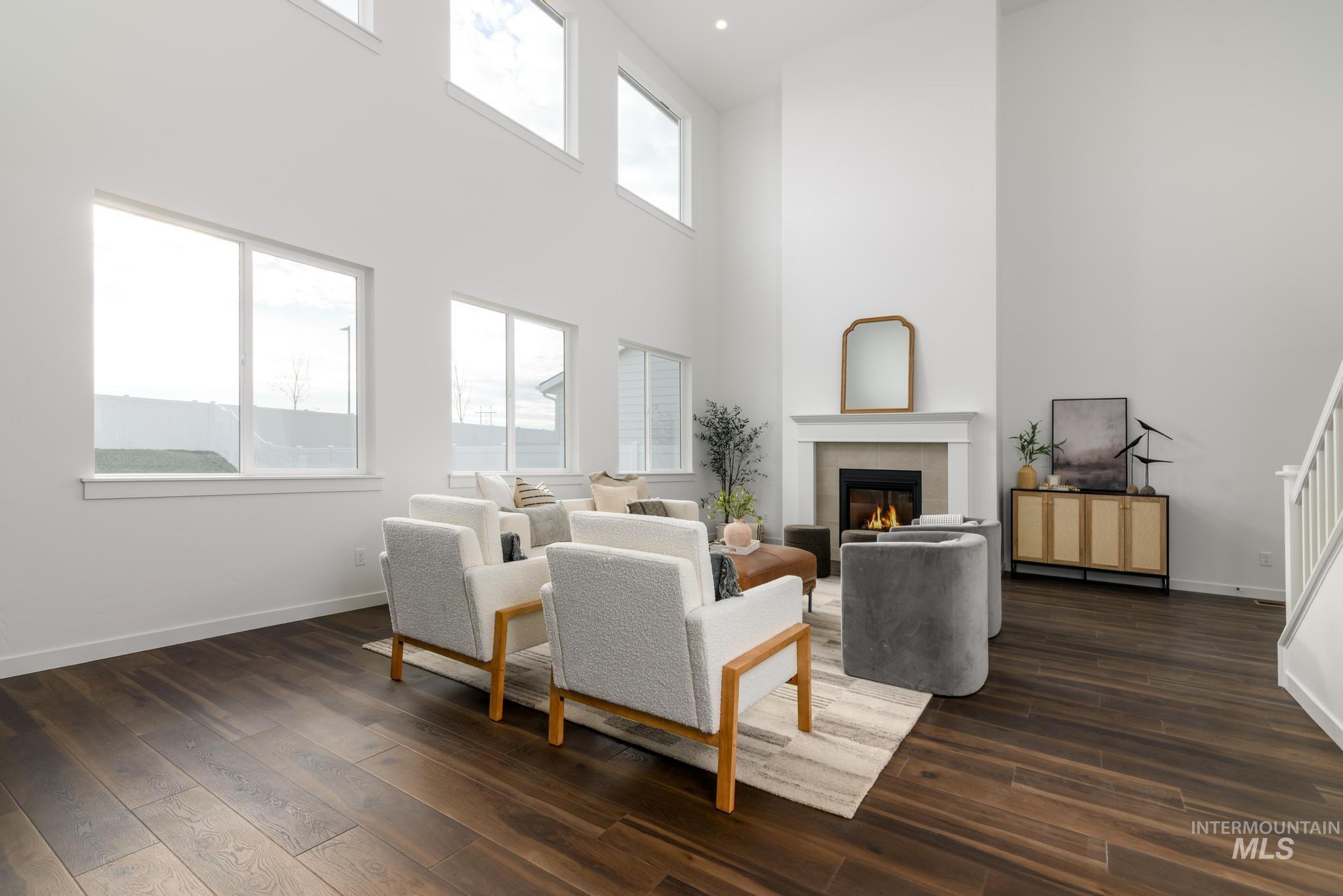 Living area featuring a tile fireplace, a high ceiling, and dark wood-type flooring