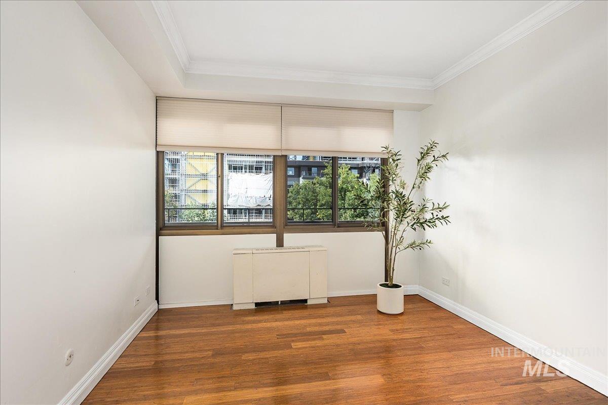 Unfurnished room with wood finished floors and ornamental molding