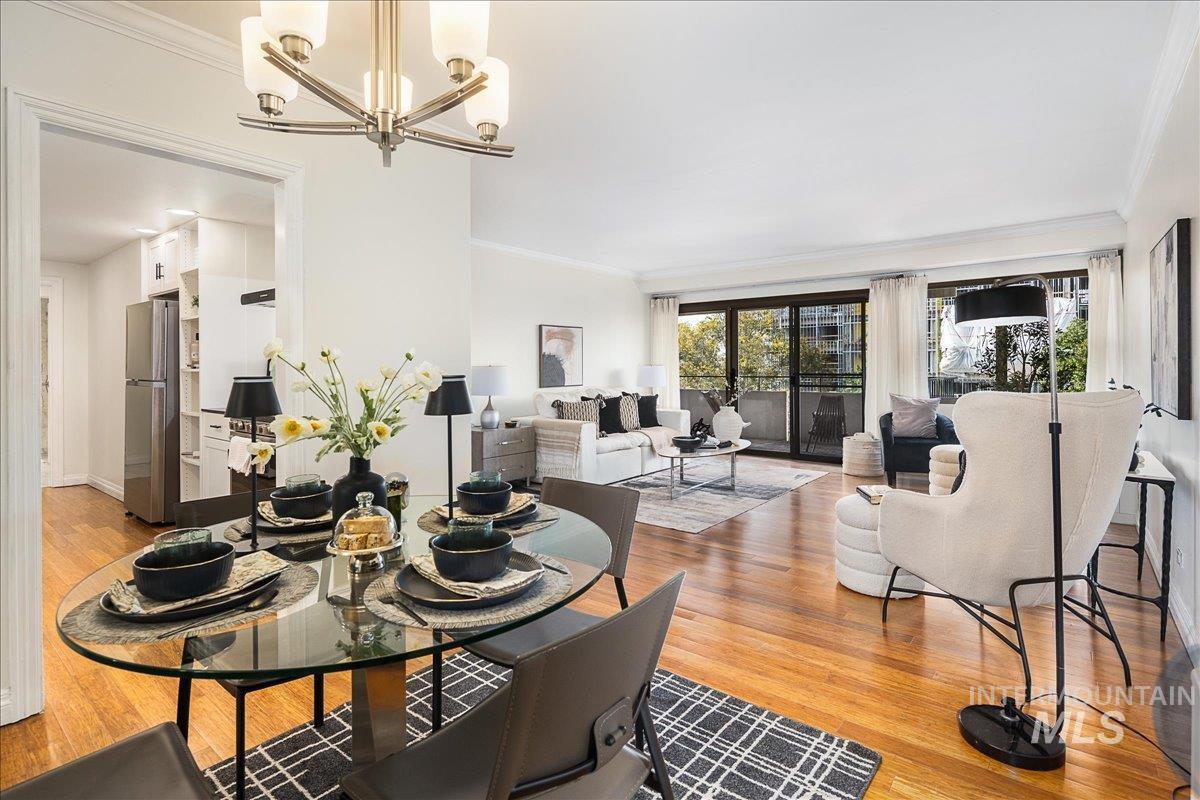 Dining space with ornamental molding, light wood-style floors, and a chandelier
