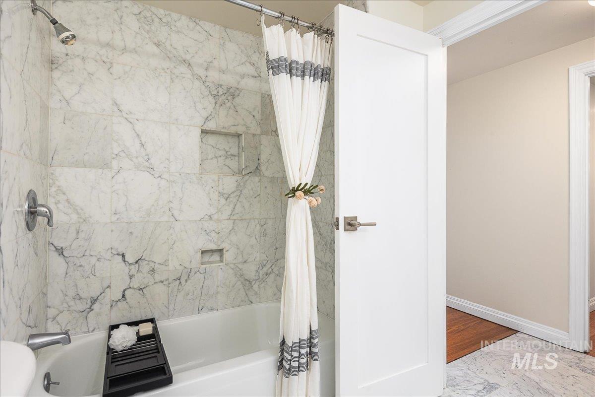 Full bathroom featuring shower / bath combination with curtain and baseboards