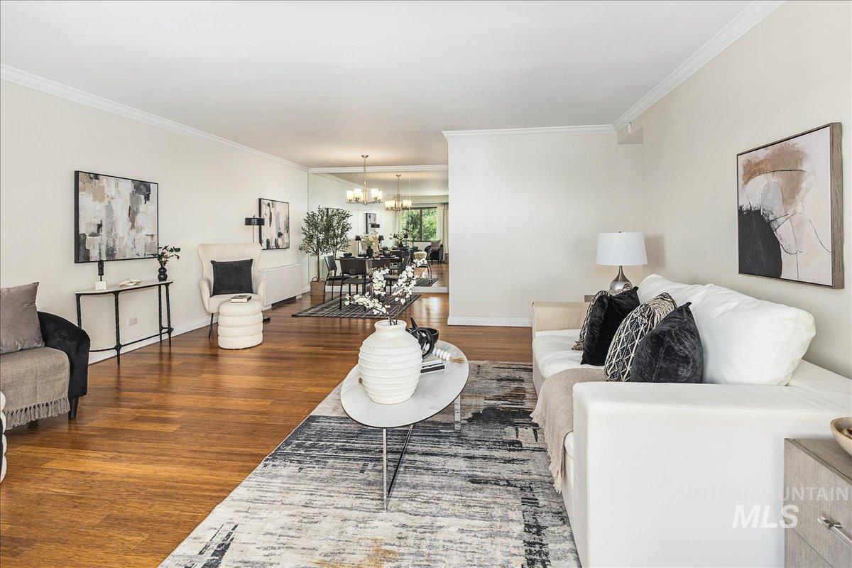 Living room with wood finished floors, crown molding, and a chandelier