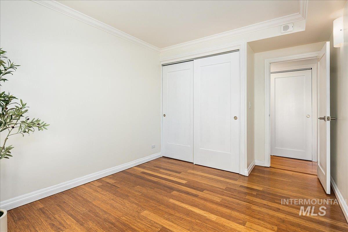 Unfurnished bedroom with crown molding, wood finished floors, and a closet