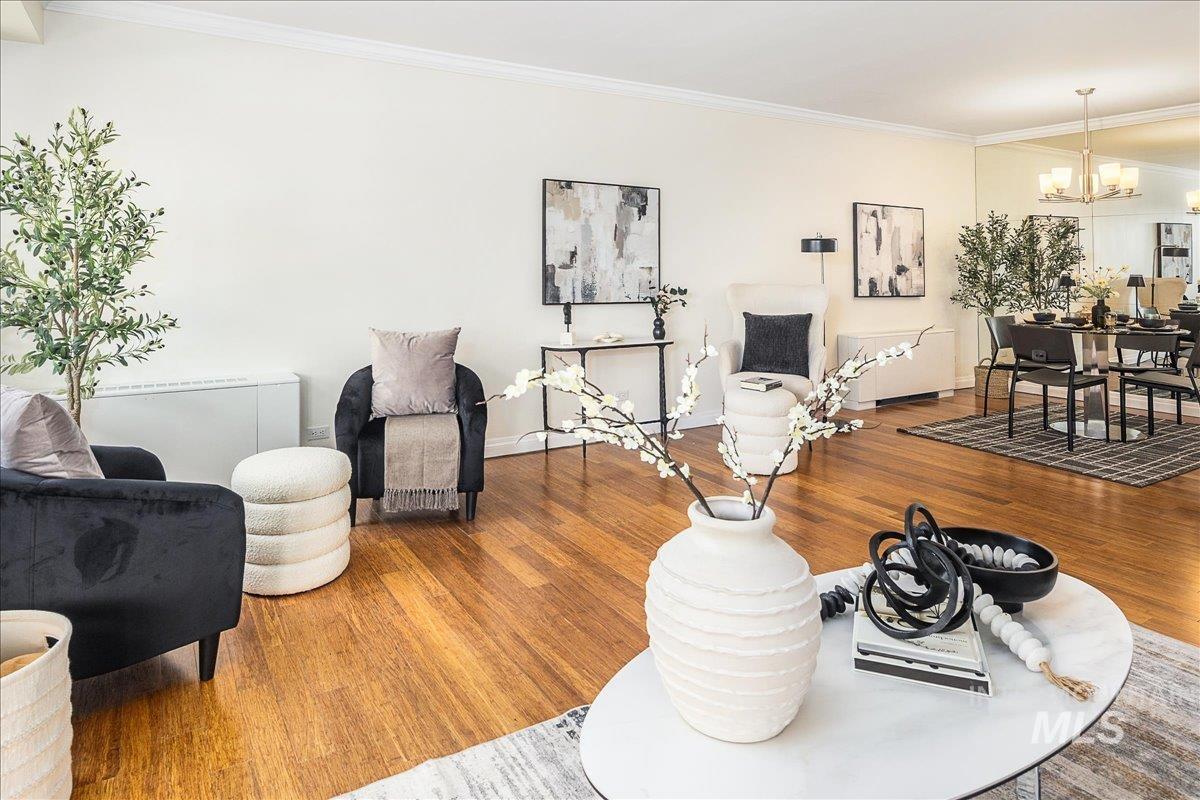 Living room with crown molding, wood finished floors, and a chandelier