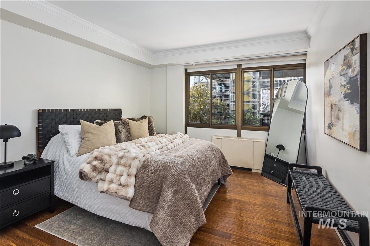 Bedroom with dark wood-style floors, crown molding, and radiator