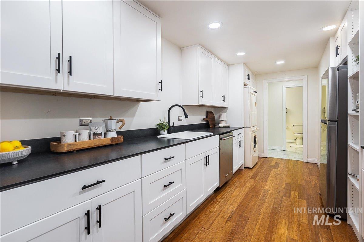 Kitchen featuring dark countertops, white cabinets, dark wood-style flooring, stainless steel appliances, and recessed lighting