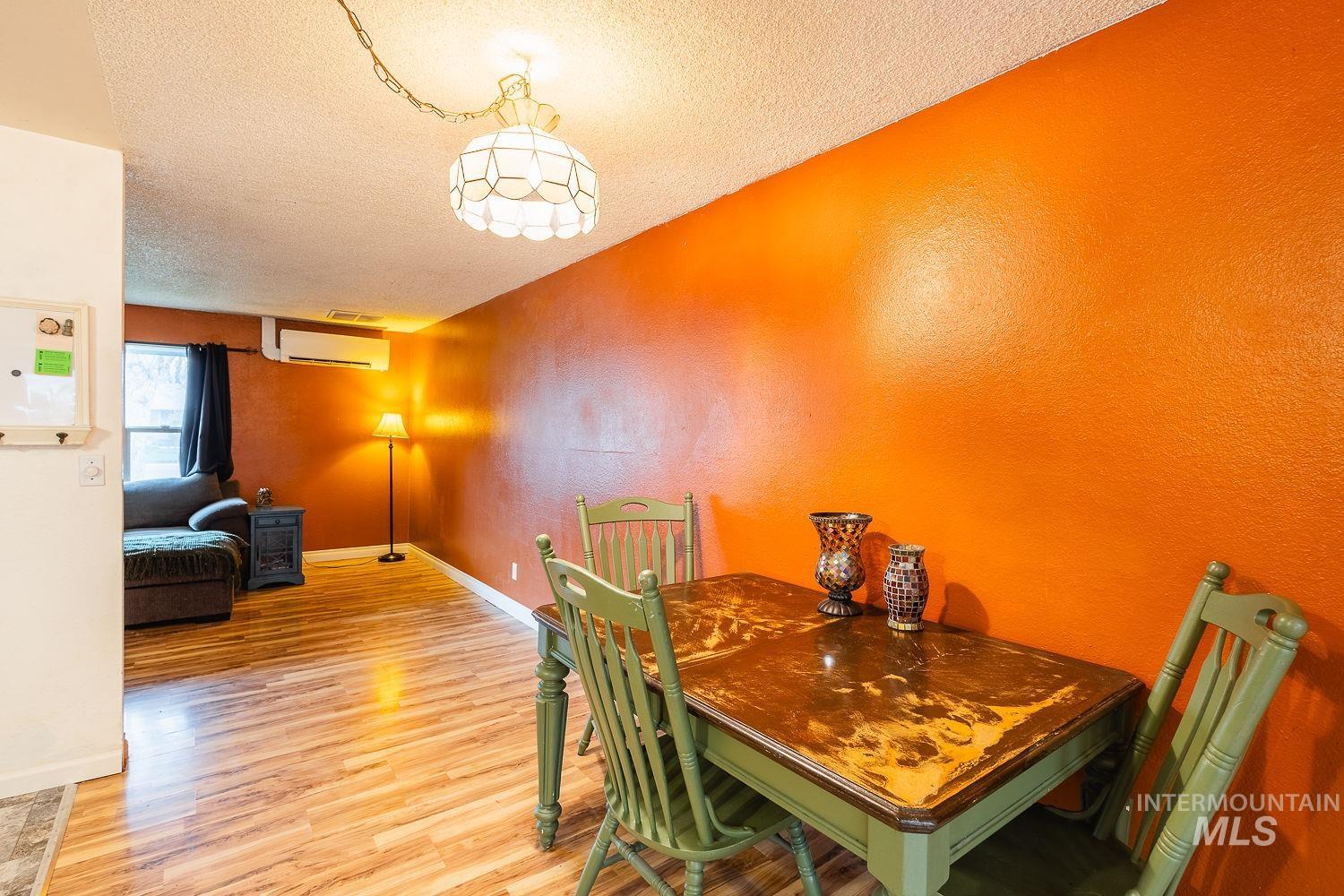 Dining area featuring a textured ceiling, a textured wall, and light wood finished floors