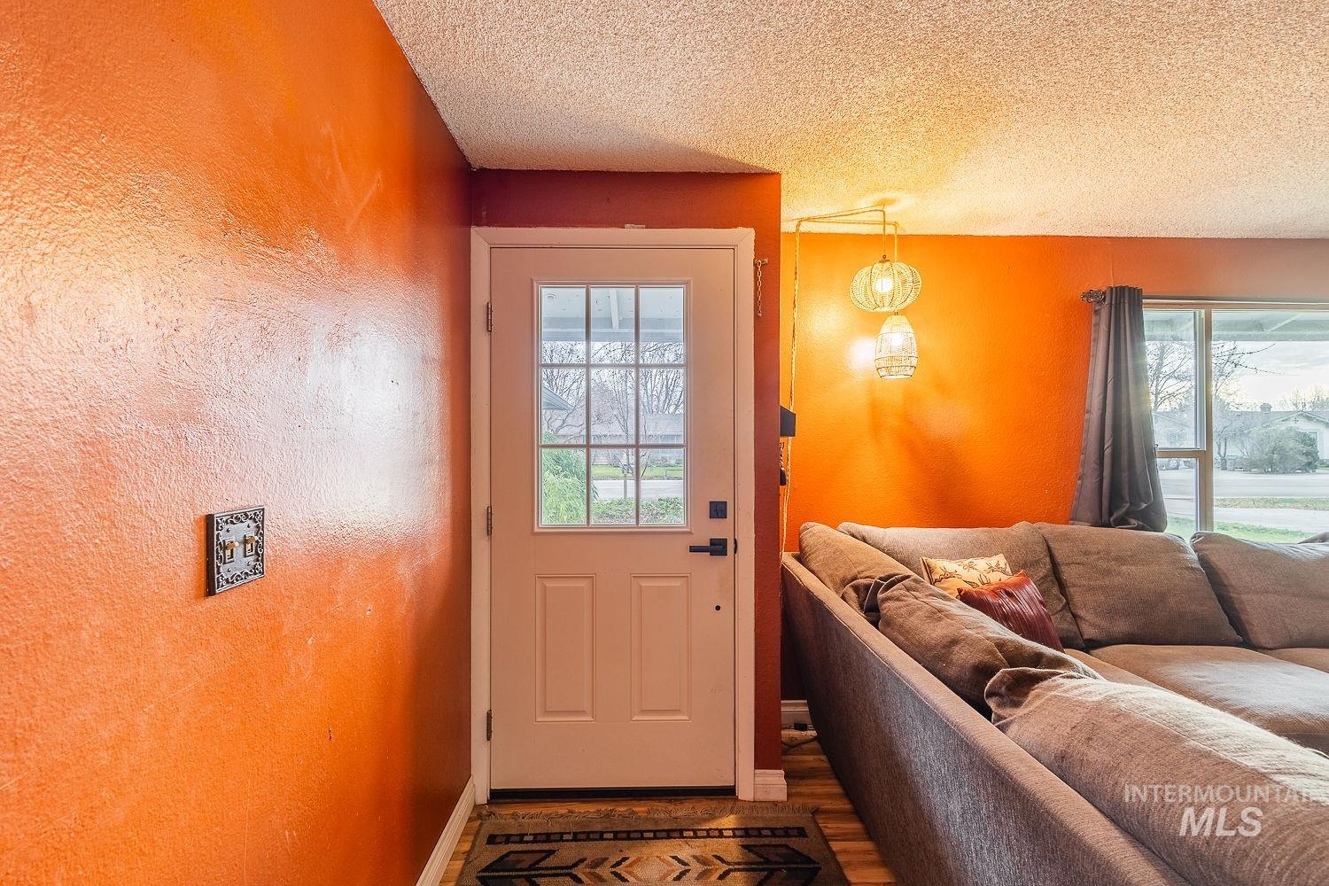 Entryway featuring a textured ceiling, plenty of natural light, a textured wall, and wood finished floors