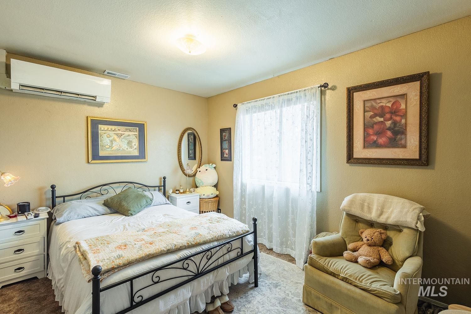 Carpeted bedroom featuring a wall mounted AC, a textured wall, and a textured ceiling