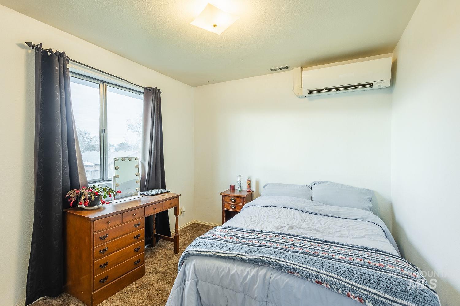 Bedroom featuring dark colored carpet and a wall mounted AC