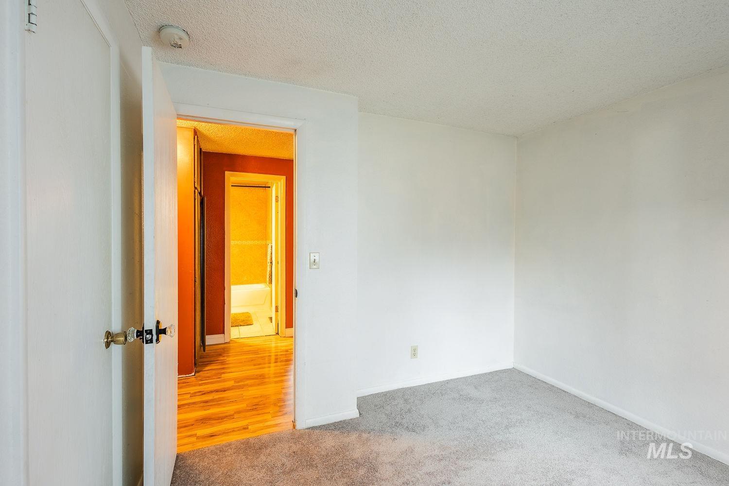 Carpeted spare room with a textured ceiling and baseboards