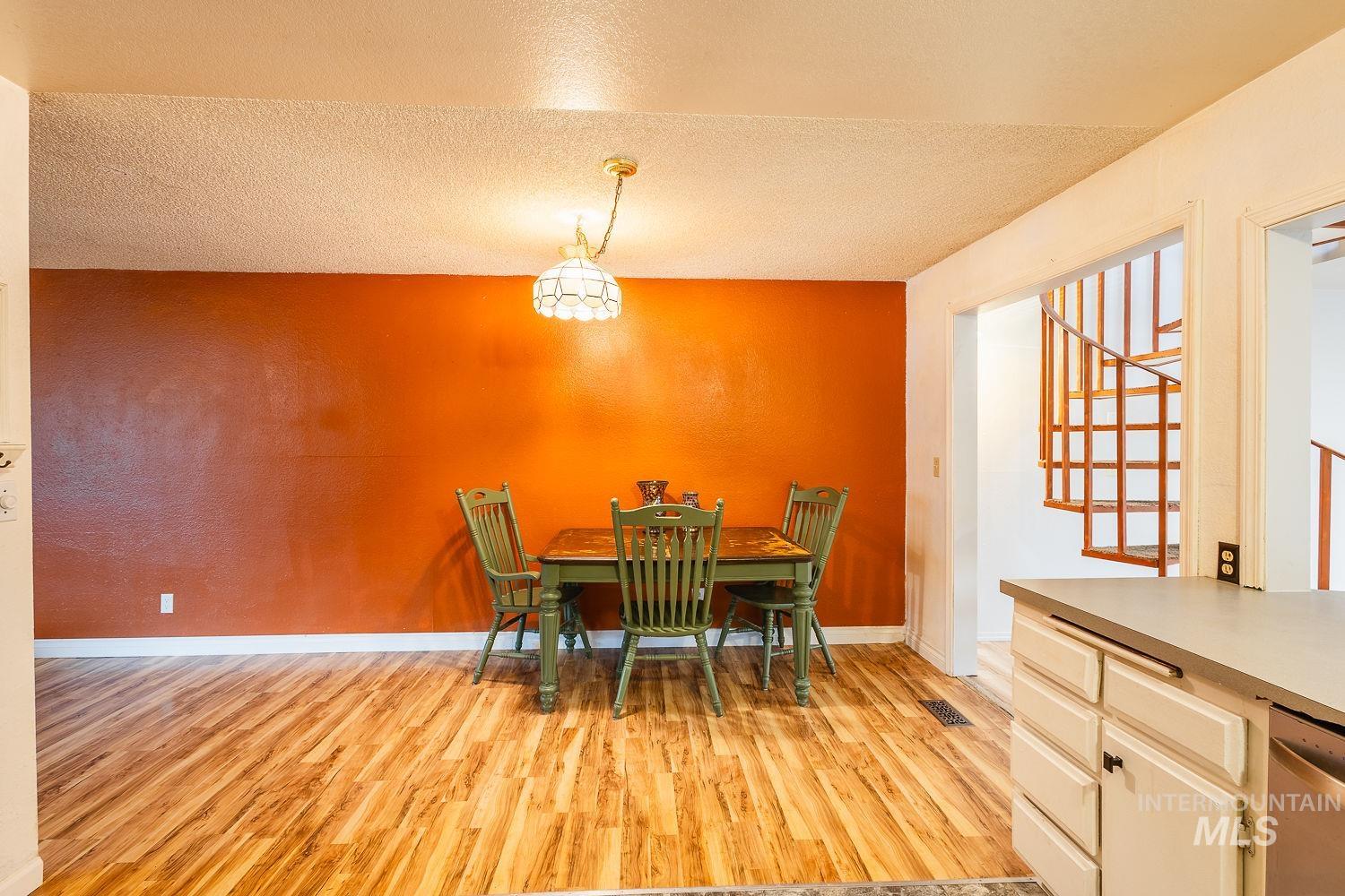 Dining area featuring light wood finished floors, a textured ceiling, and stairway