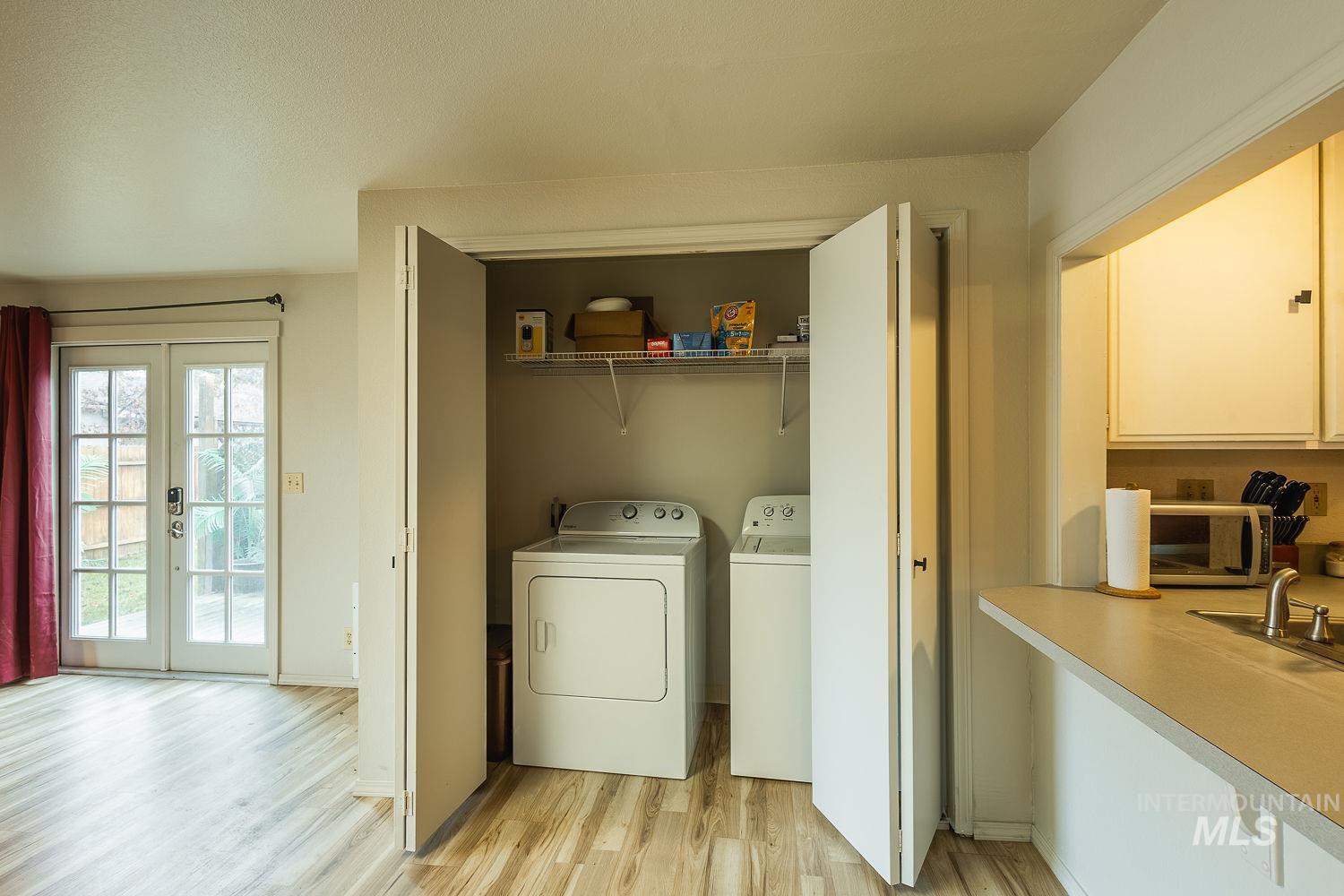 Laundry area featuring independent washer and dryer, light wood-type flooring, and french doors