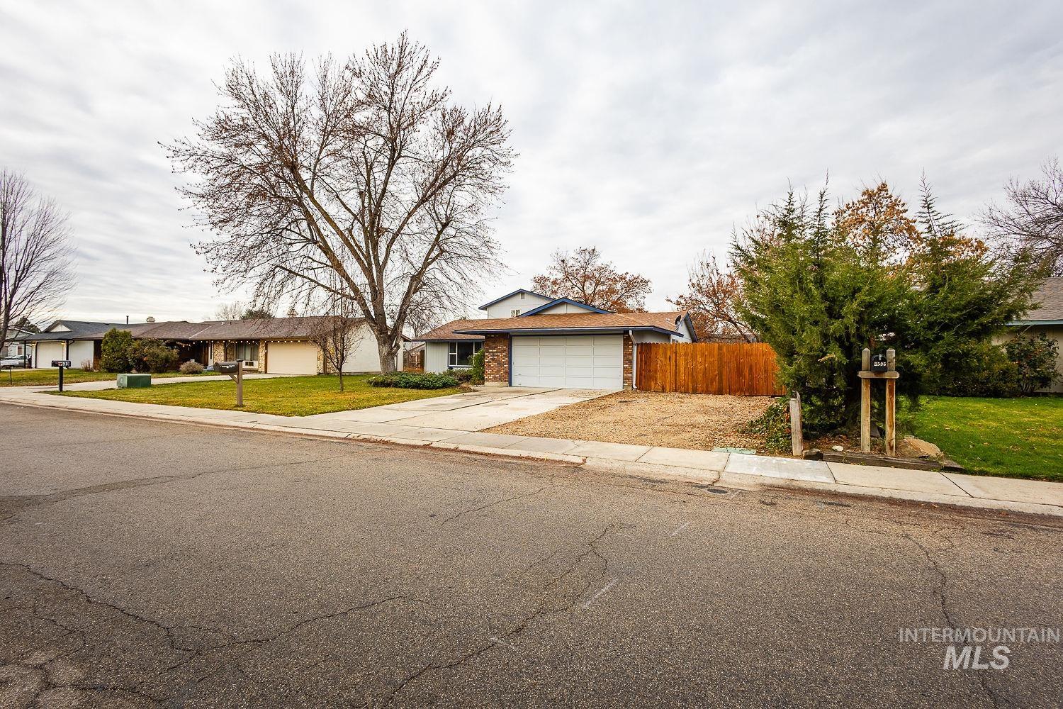 View of front of house with concrete driveway, an attached garage, brick siding, and a residential view