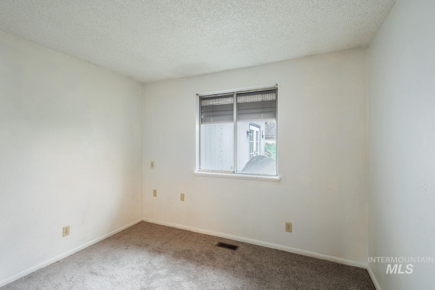 Carpeted spare room with a textured ceiling and baseboards