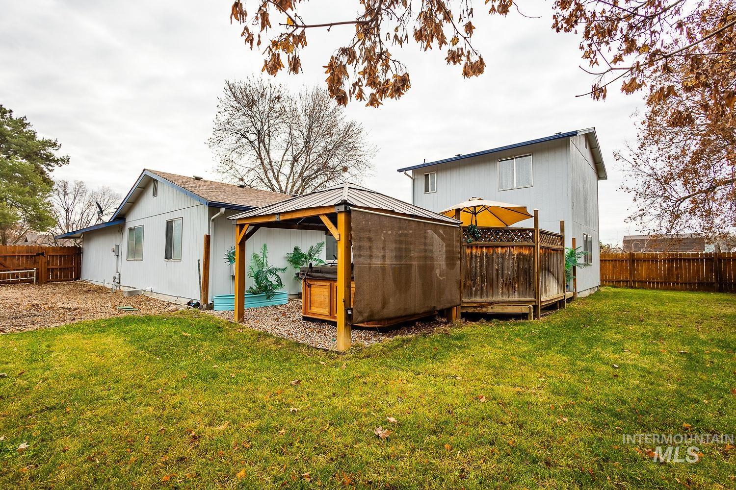 Rear view of house featuring a fenced backyard, a deck, and a gazebo