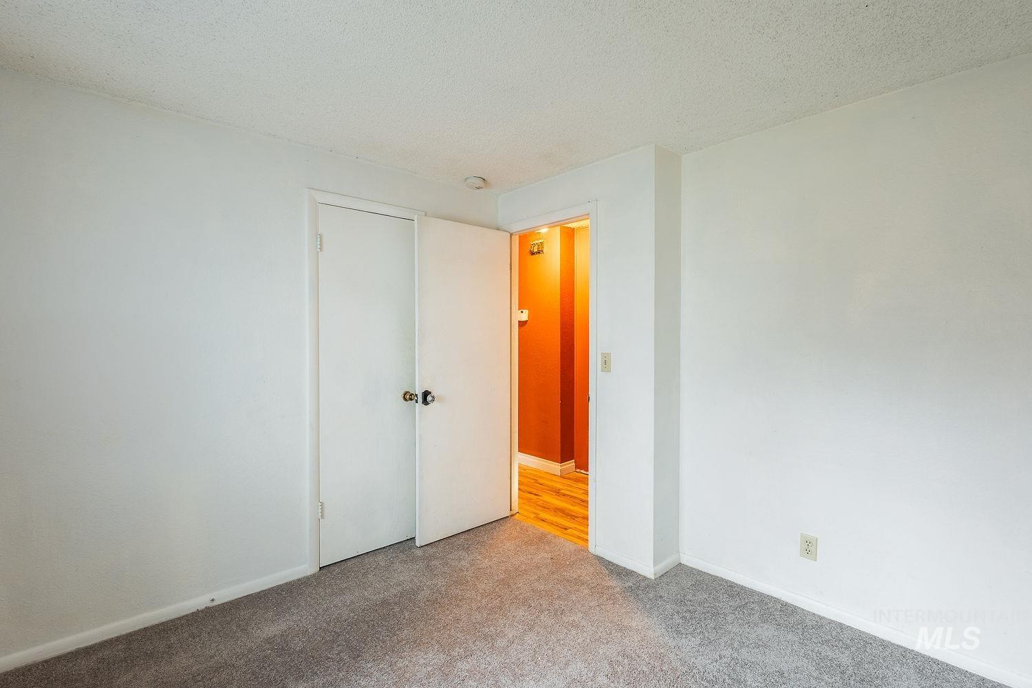Carpeted empty room featuring a textured ceiling and baseboards