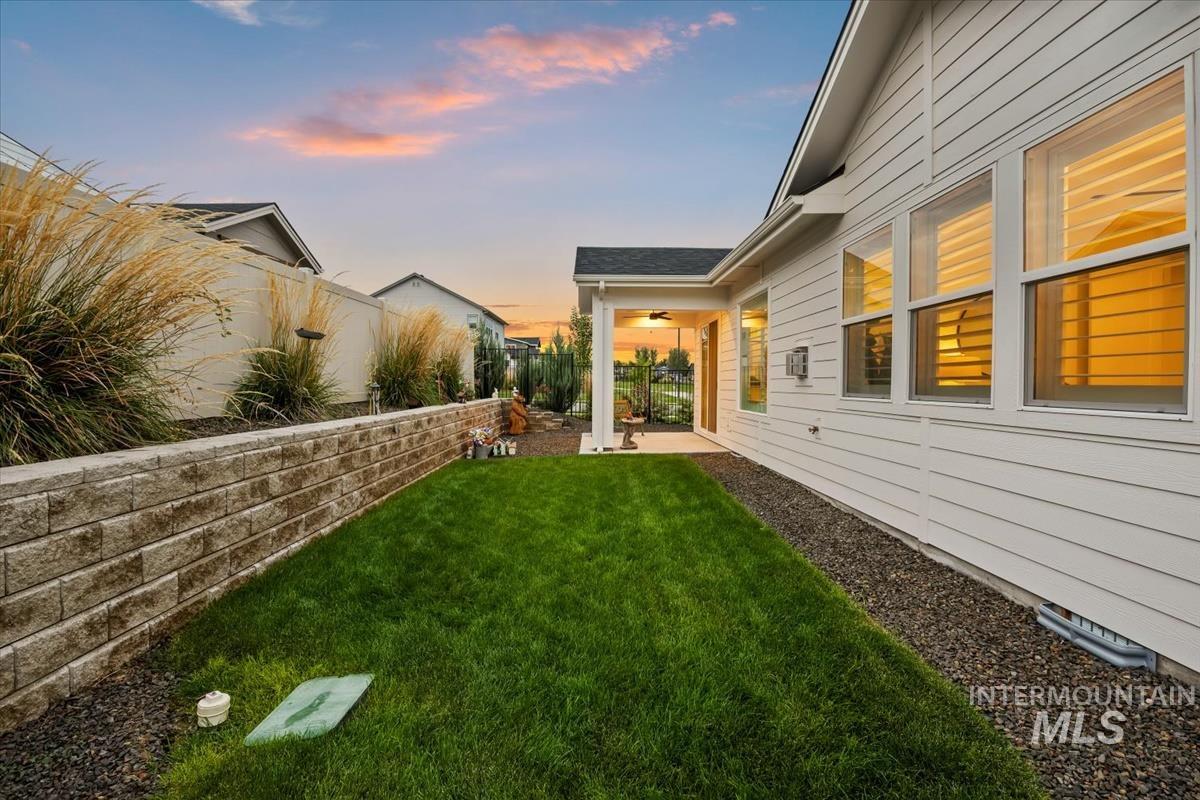 Yard at dusk featuring a patio, a fenced backyard, and a ceiling fan