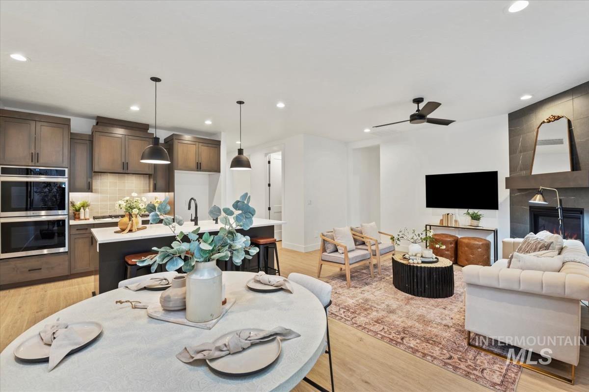 Dining room featuring light wood finished floors, recessed lighting, a large fireplace, and ceiling fan