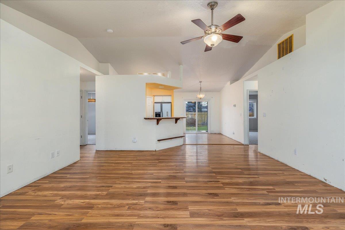 Unfurnished living room with vaulted ceiling, dark wood-type flooring, and a ceiling fan