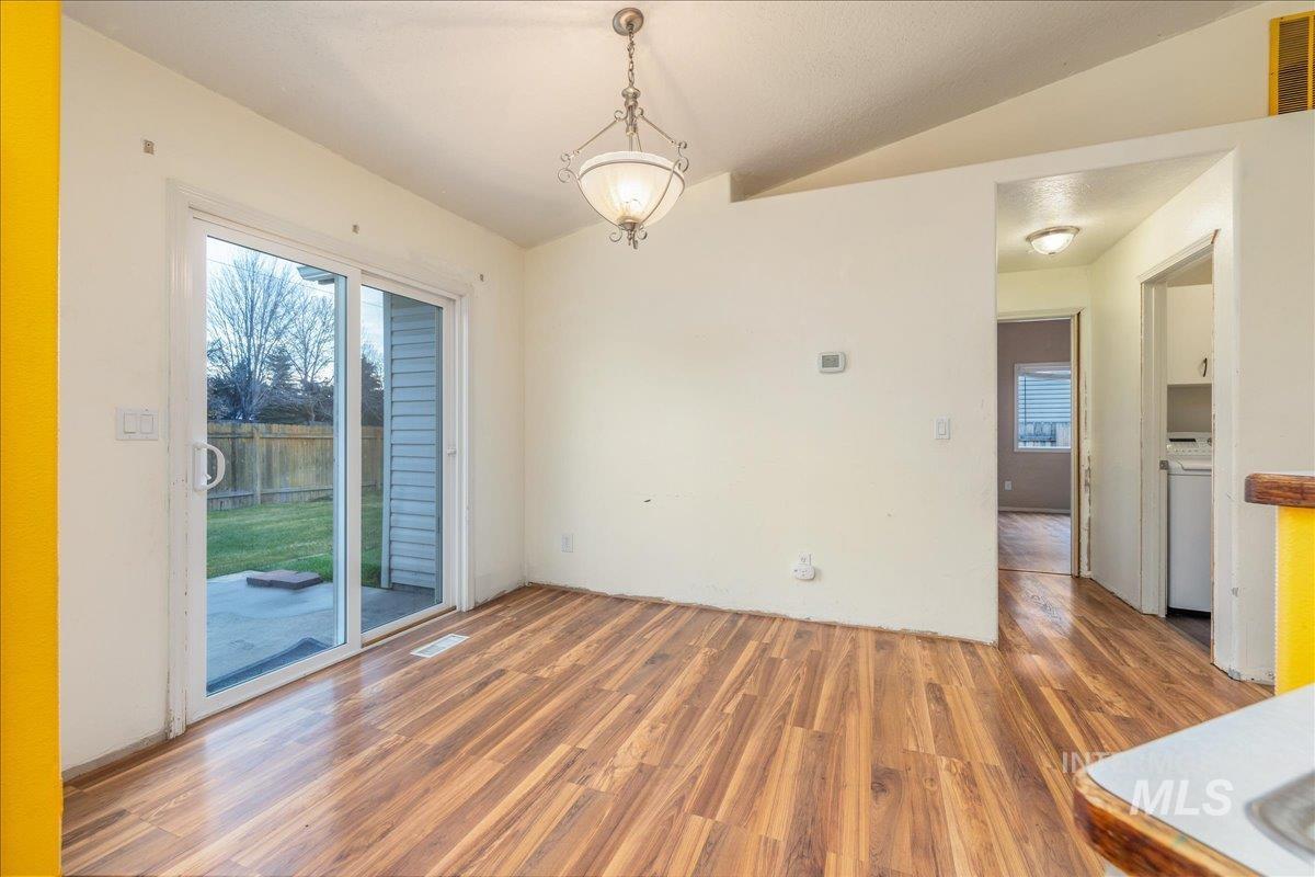 Unfurnished dining area with vaulted ceiling and wood finished floors