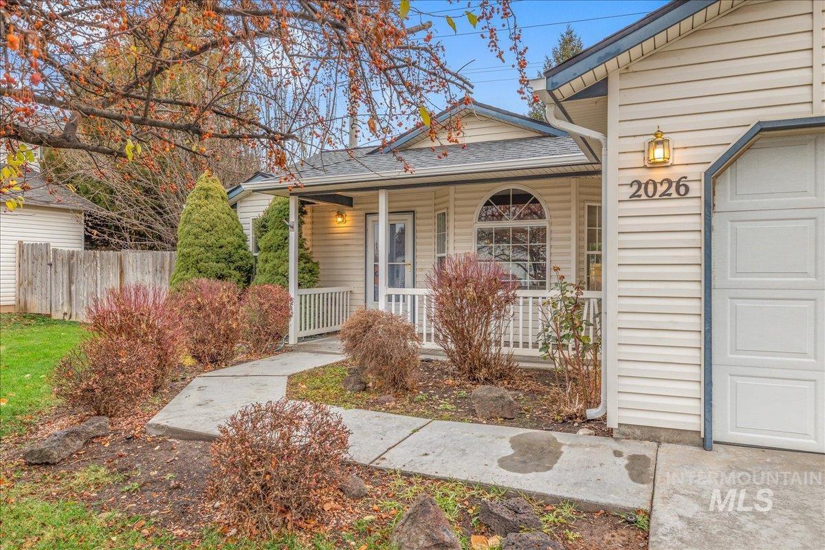 Doorway to property with a porch and a shingled roof