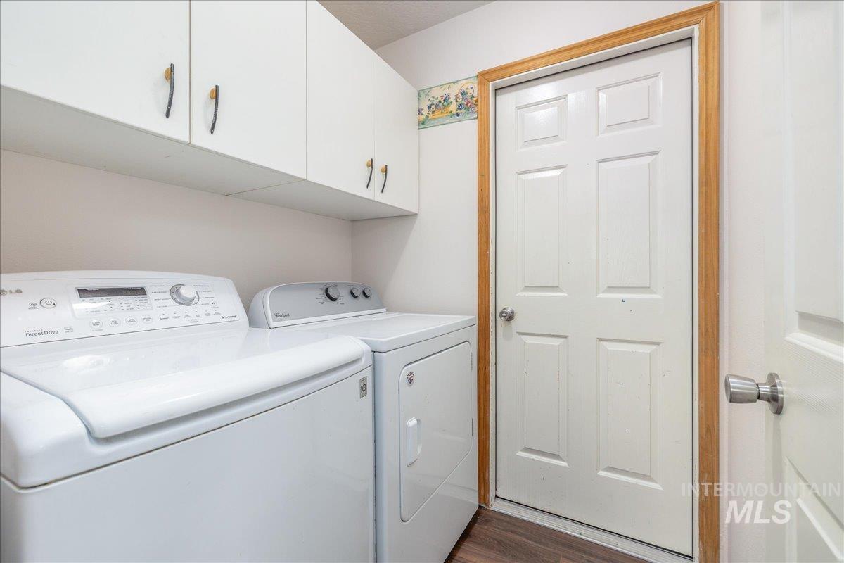 Washroom with washing machine and clothes dryer, cabinet space, and dark floors