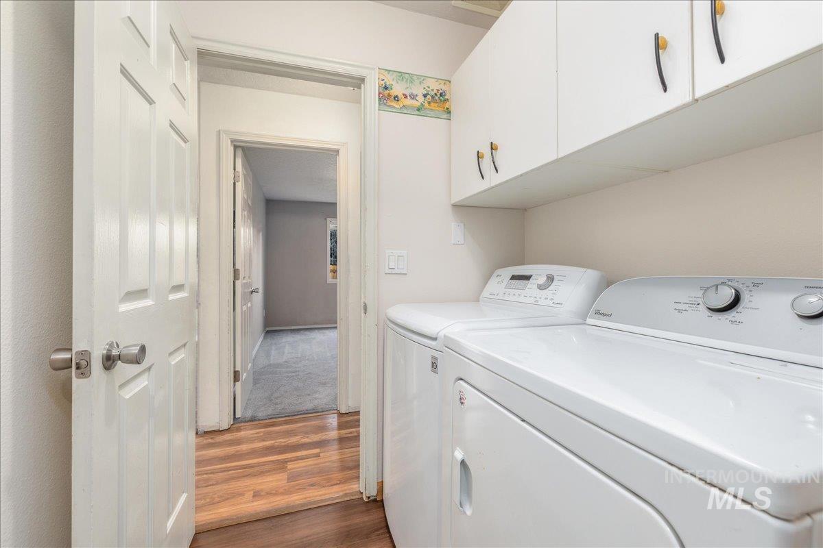 Washroom featuring dark flooring, washing machine and clothes dryer, and cabinet space