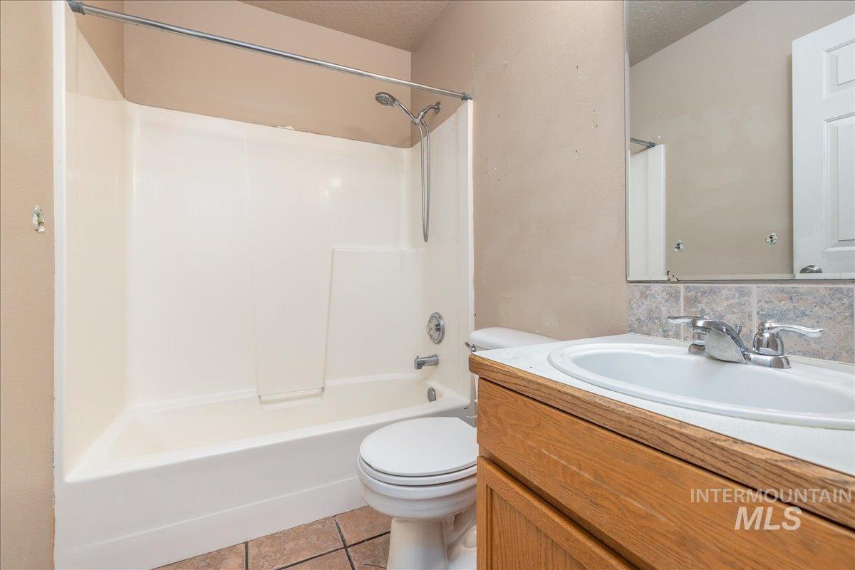 Full bathroom with vanity, washtub / shower combination, light tile patterned flooring, and a textured ceiling