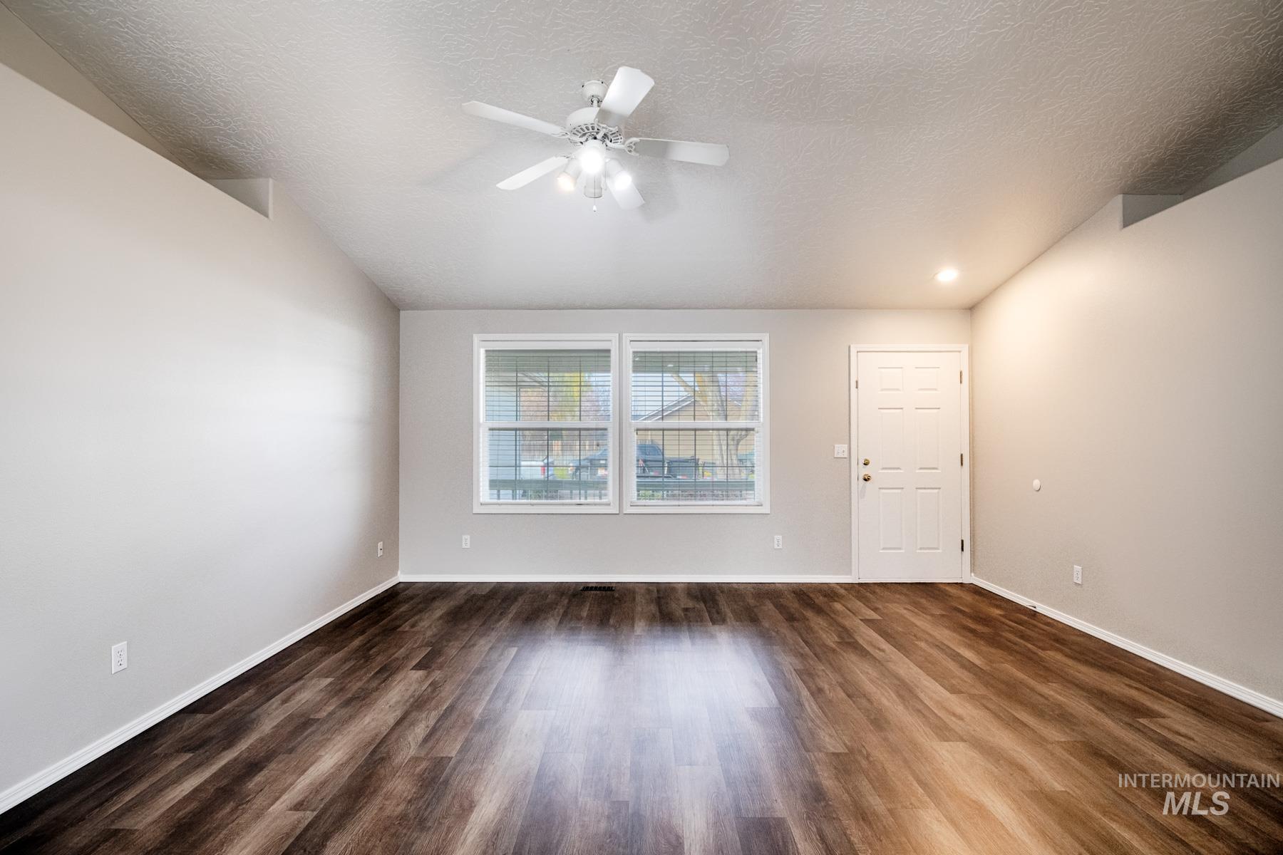 Empty room with dark wood-type flooring, a ceiling fan, and a textured ceiling