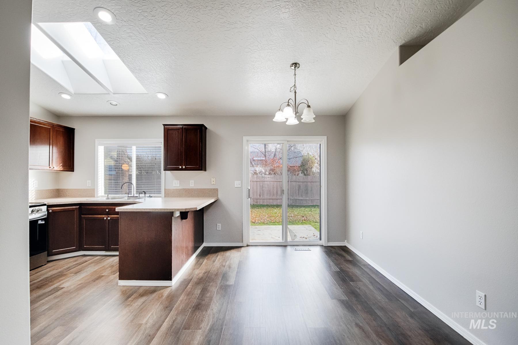 Kitchen featuring a peninsula, dark brown cabinets, a breakfast bar, a skylight, and healthy amount of natural light