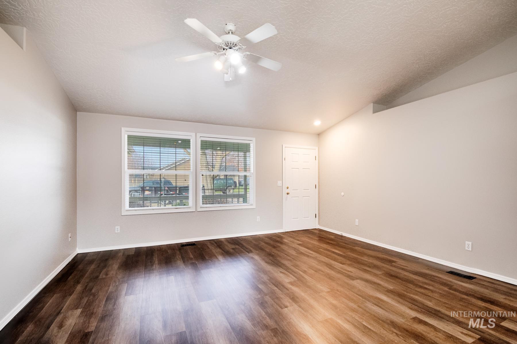 Unfurnished room featuring vaulted ceiling, dark wood-type flooring, recessed lighting, ceiling fan, and a textured ceiling