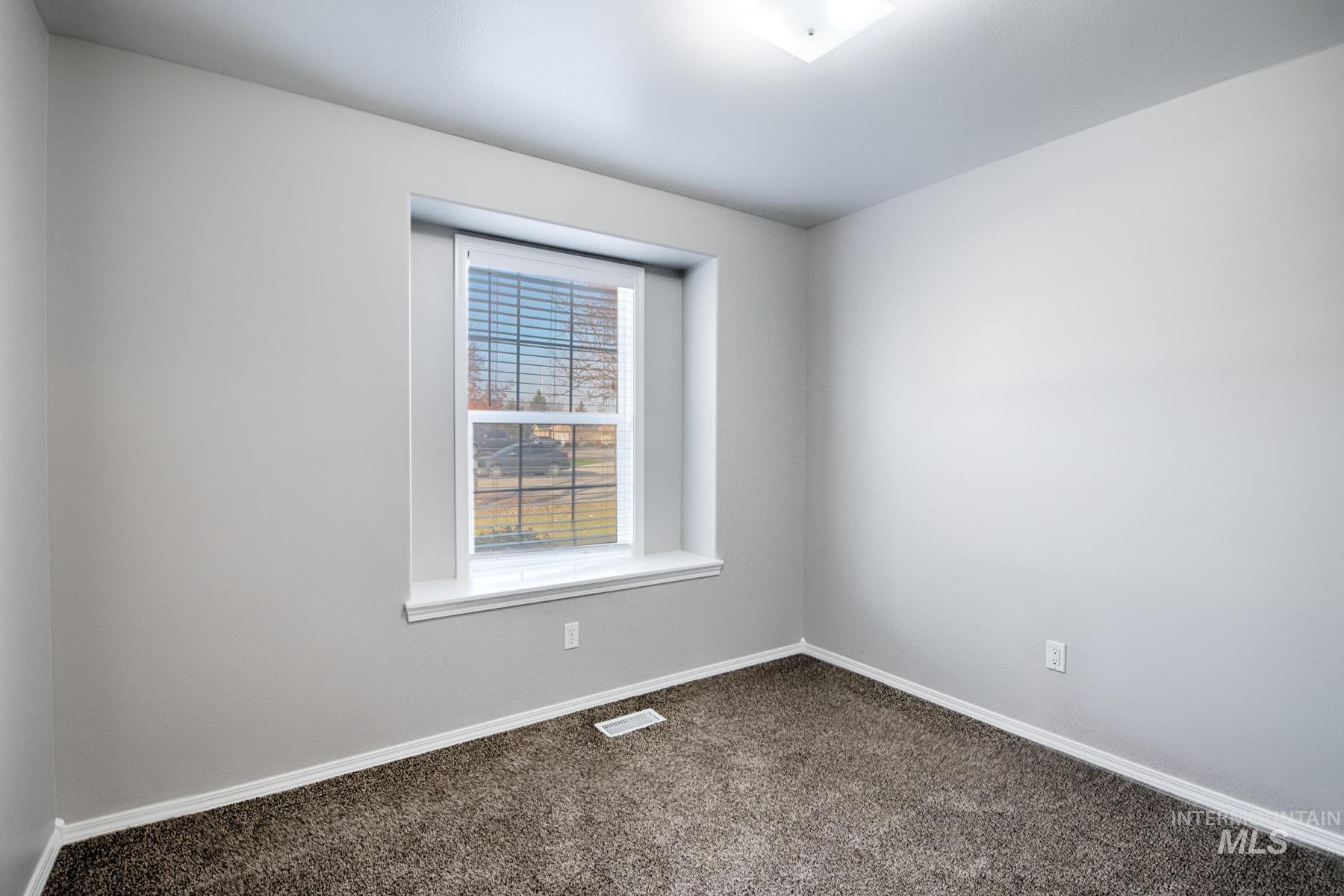 Spare room with baseboards and dark carpet